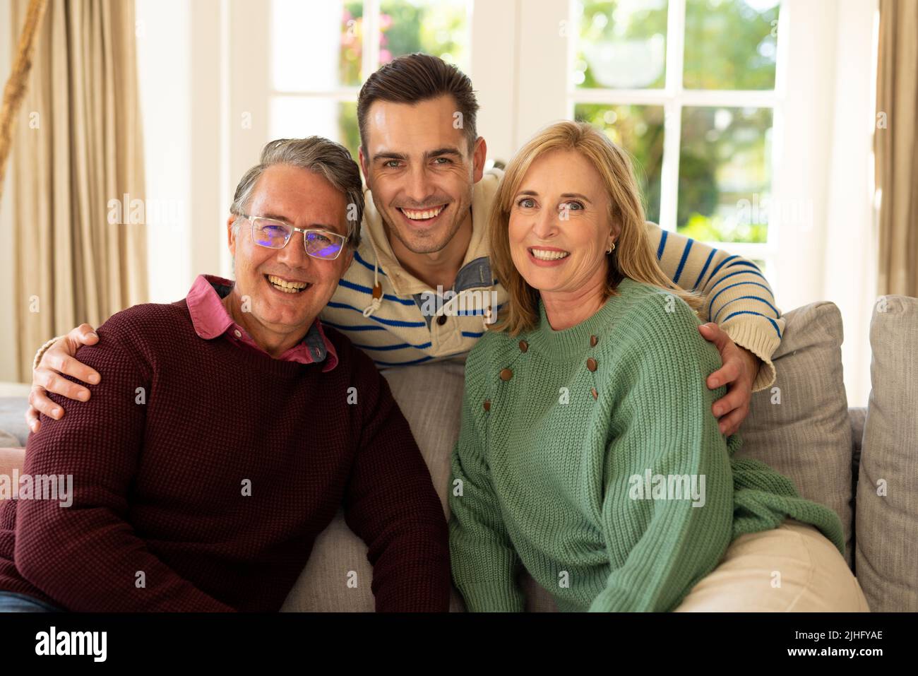 Image de parents caucasiens heureux et de fils adultes assis sur le canapé et souriant Banque D'Images