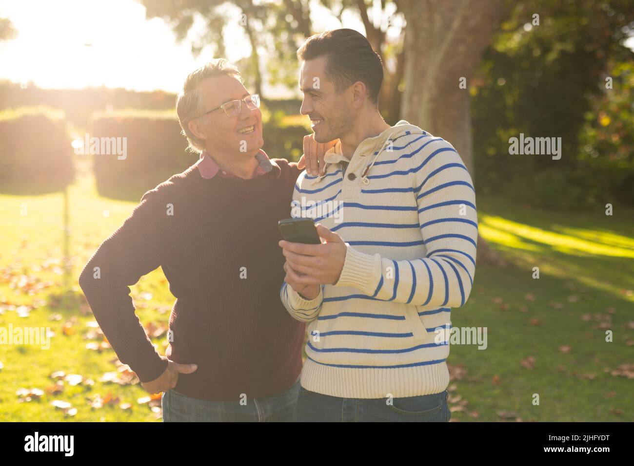 Image d'un père caucasien heureux et d'un fils adulte prenant le selfie dans le jardin Banque D'Images