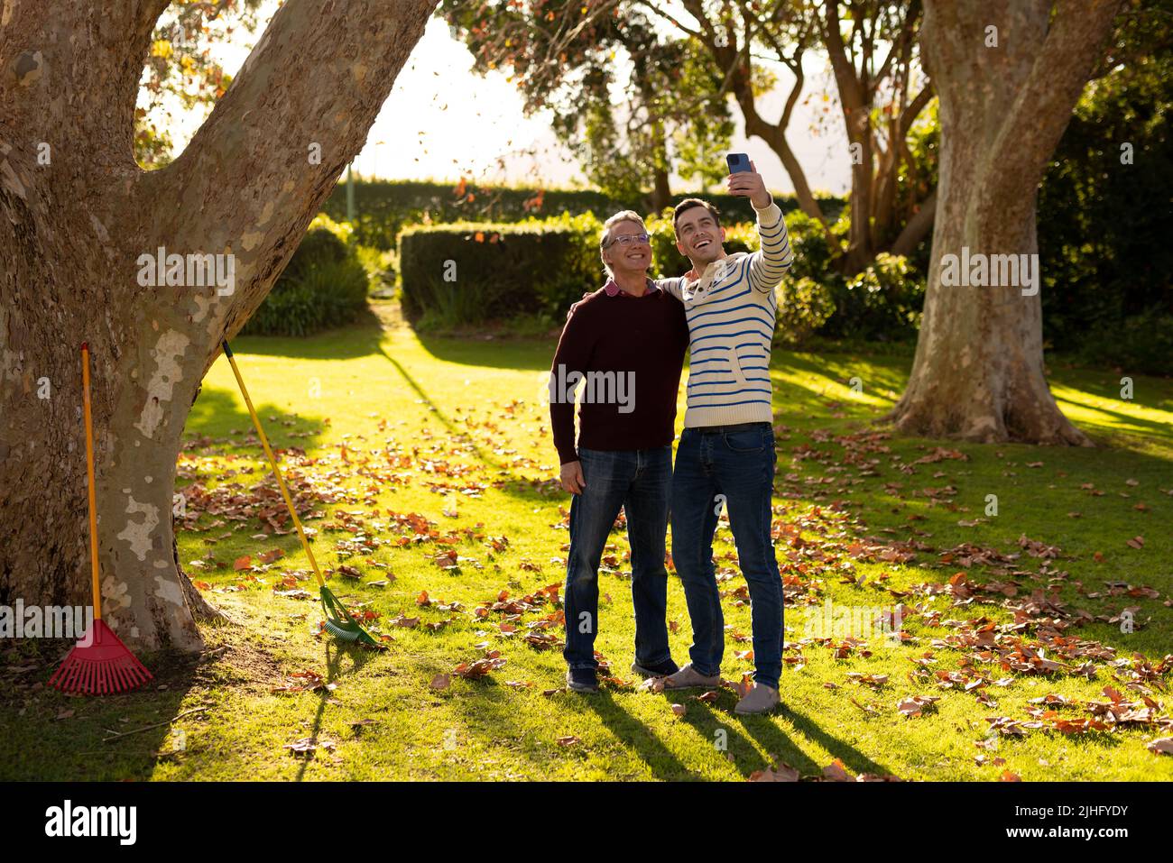 Image d'un père caucasien heureux et d'un fils adulte prenant le selfie dans le jardin Banque D'Images