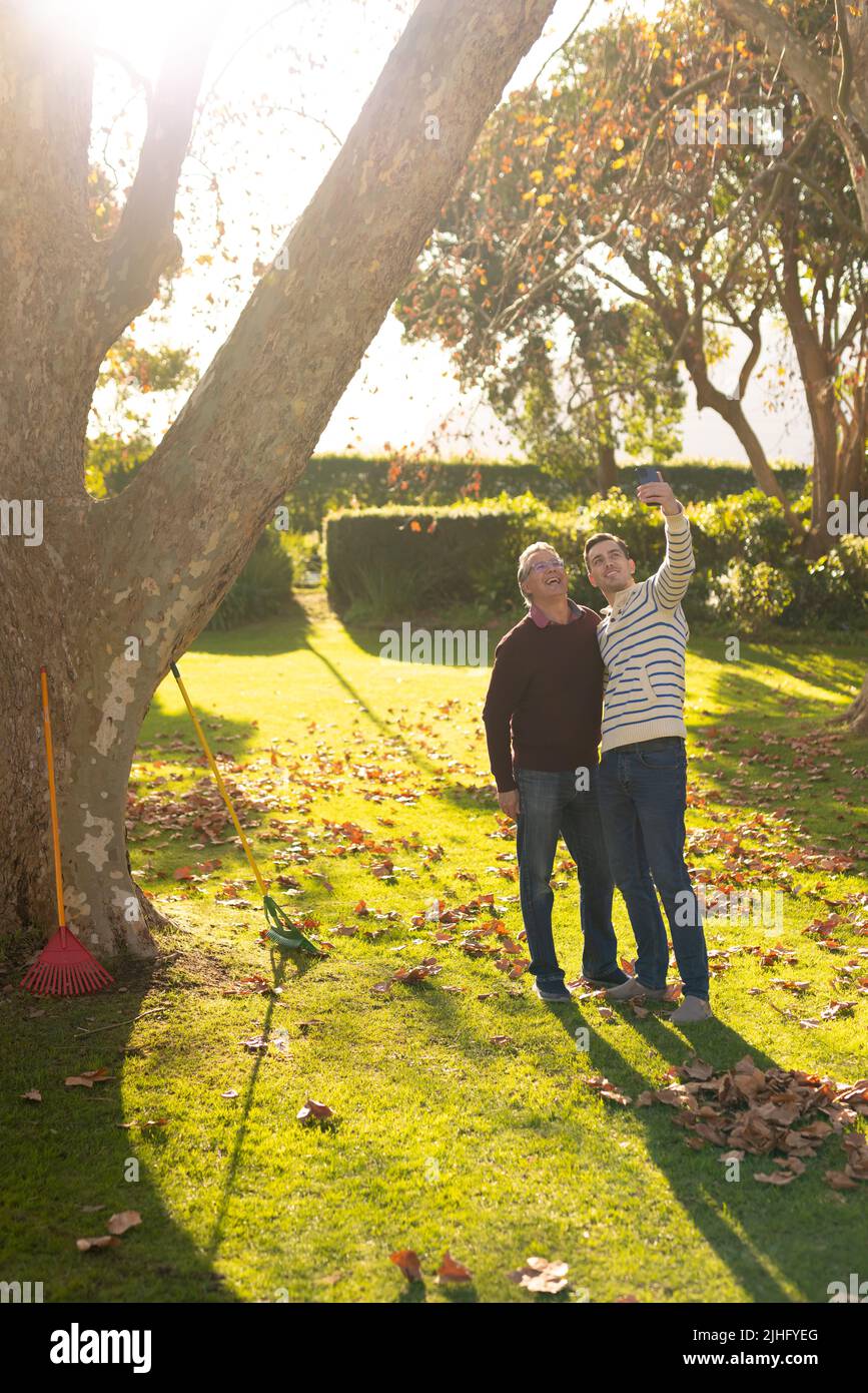 Image verticale de père caucasien heureux et de fils adultes prenant selfie dans le jardin Banque D'Images