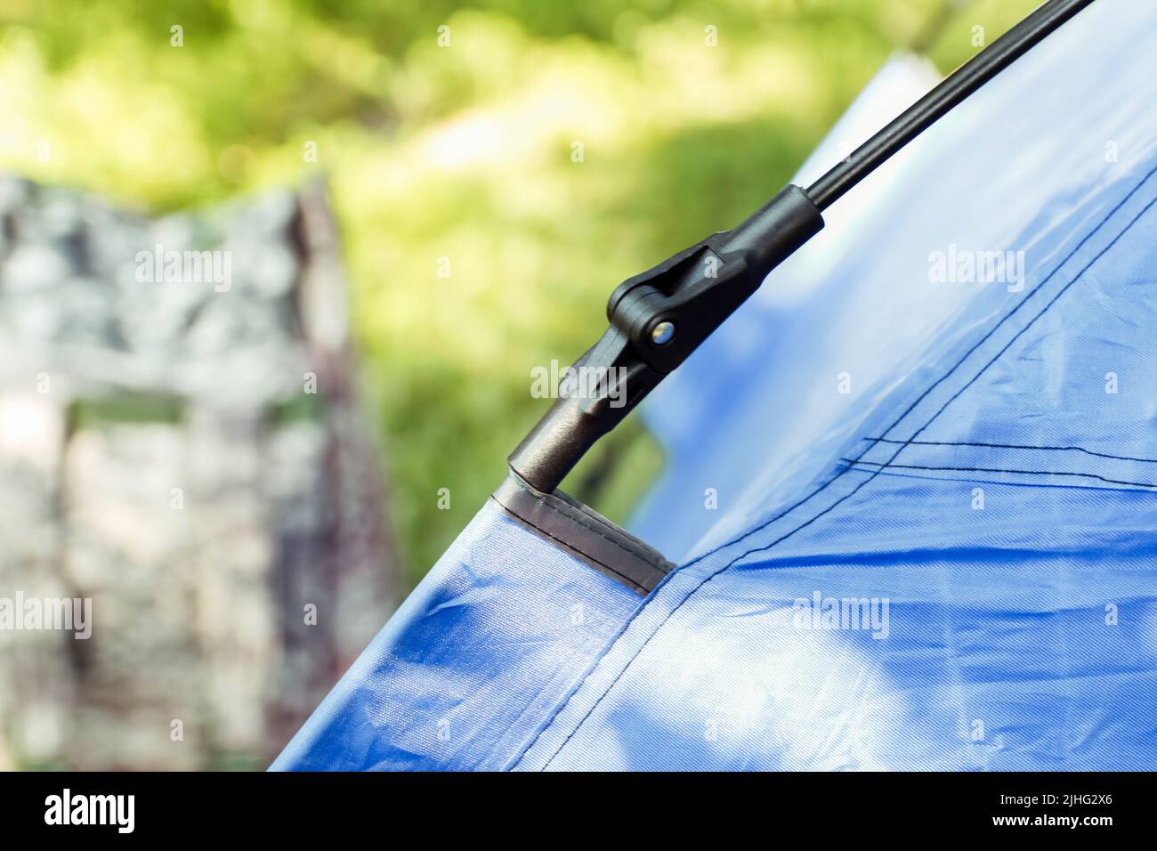 Flou artistique en gros plan tente touristique bleue debout sur fond vert nature. Sac à dos militaire. Concept du tourisme. Vacances d'été en forêt, camping. Chasseur Banque D'Images