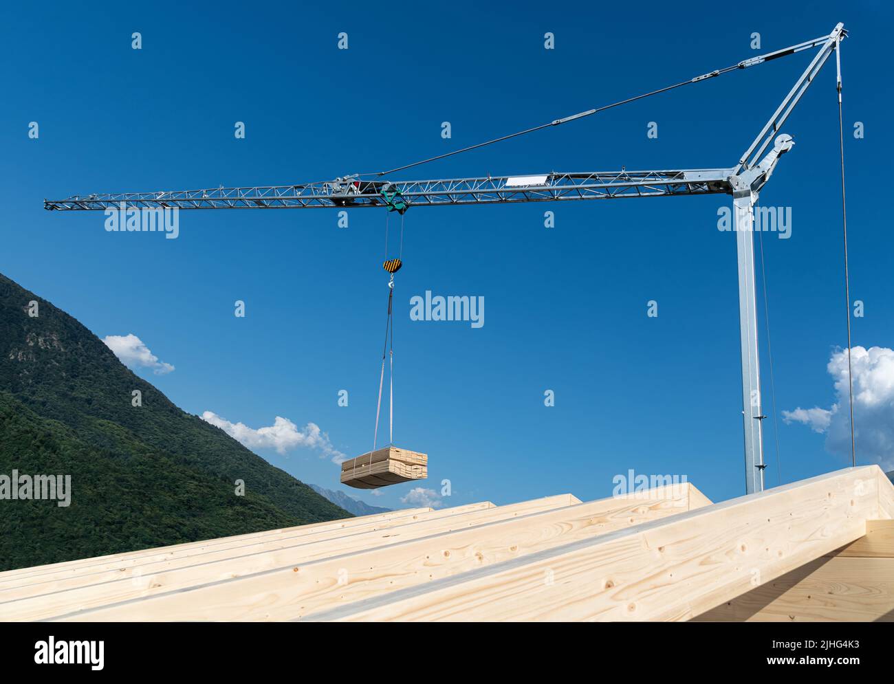 Grue de construction avec charge suspendue de planche en bois sur un ciel bleu Banque D'Images
