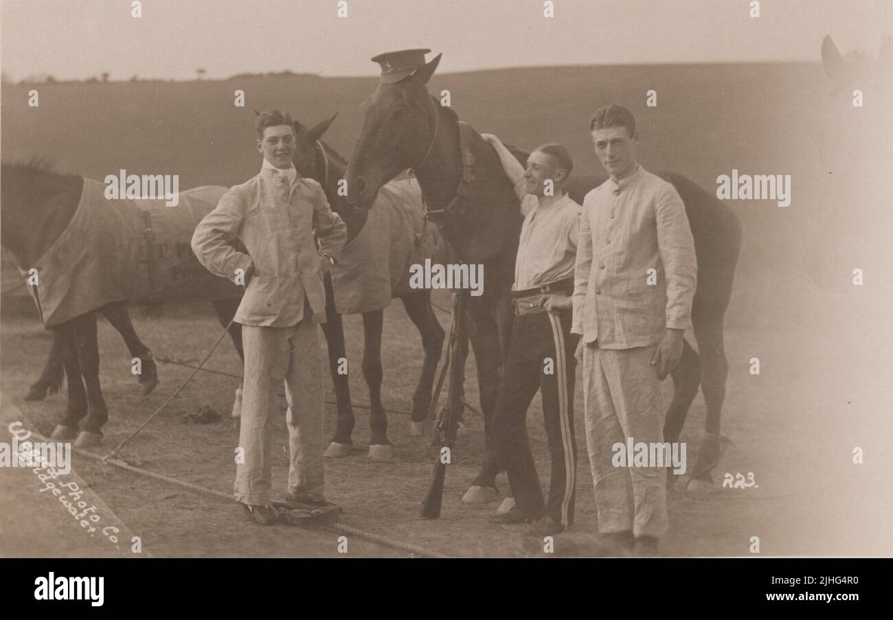 Queen's Own West Kent Yeomanry, début du 20th siècle. Trois soldats debout avec une rangée de chevaux de l'armée. Un cheval a été vêtu d'une casquette de soldat (avec l'insigne de casquette de West Kent Yeomanry d'un cheval-piqueur), d'un bandolier et d'un fusil. Un soldat est un pantalon uniforme et une chemise, les autres portent ce qui ressemble à des costumes en lin (l'homme de gauche semble également être dans une paire de chaussons). La photo a été prise par Wessex photo Co., Bridgewater Banque D'Images