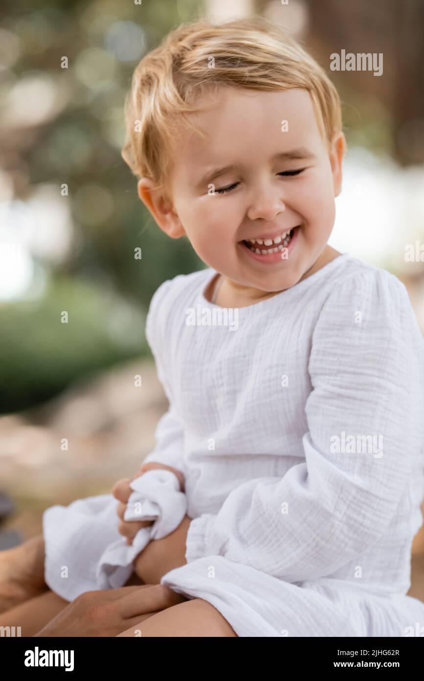 Joyeux enfant en robe assis près de maman à l'extérieur Banque D'Images