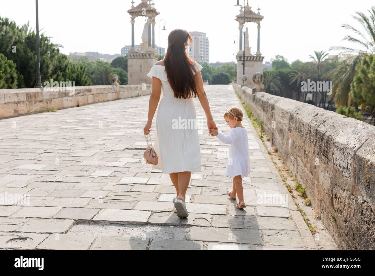 Femme en robe tenant la main de la petite fille tout en marchant sur le pont Puente Del Mar à Valence Banque D'Images