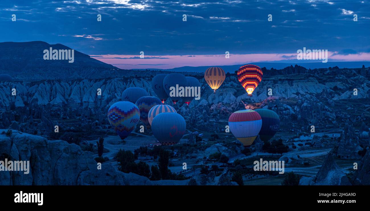 GÖREME/TURQUIE - 30 juin 2022 : des ballons à air chaud survolent la ville à l'aube Banque D'Images