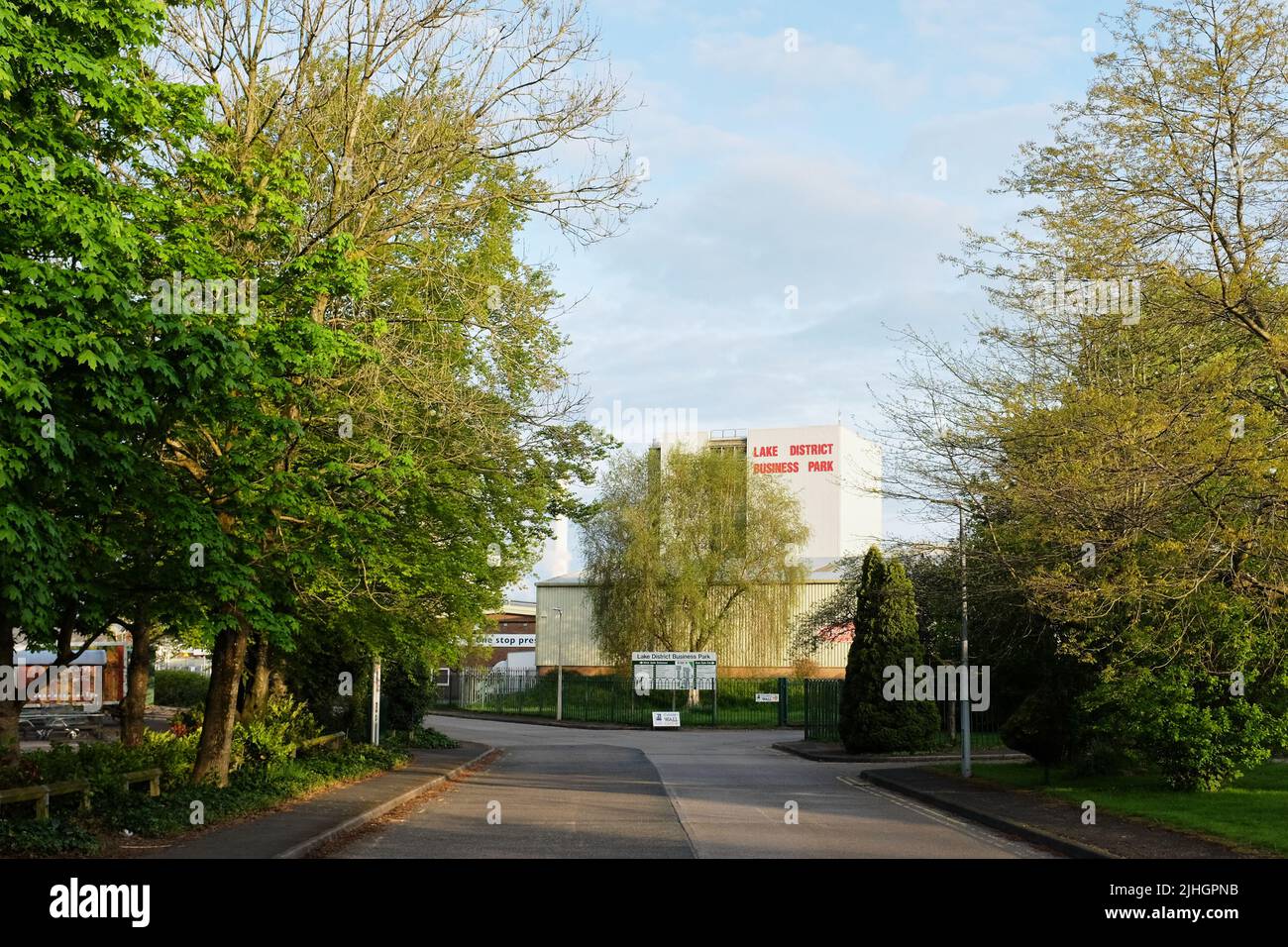 Route bordée d'arbres vers un grand bâtiment sur un parc industriel avec le panneau Lake District Business Park dessus à Kendal, Cumbria. Banque D'Images