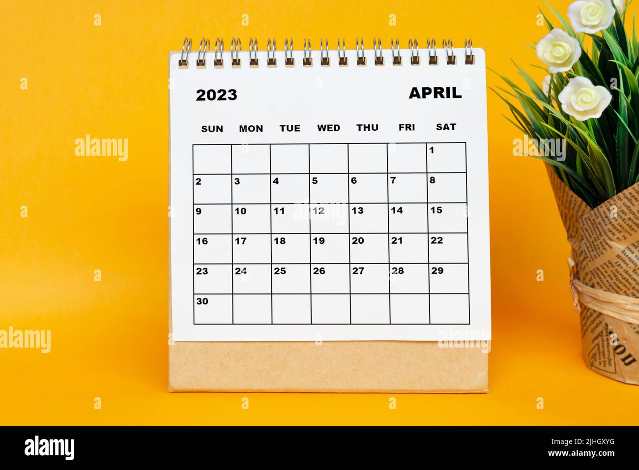 Calendrier blanc d'avril 2023 avec plante en pot sur fond jaune. Banque D'Images