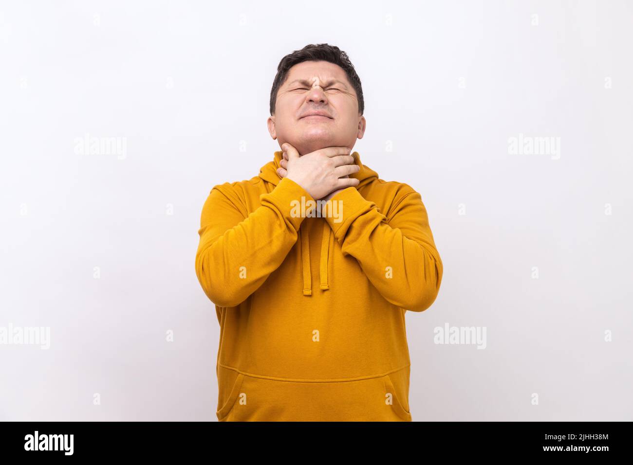 Portrait d'un homme malade de la grippe qui se sent mal au cou, souffrant de maux de gorge et d'amygdales enflammées, douleur insupportable, portant un sweat à capuche de style urbain. Studio d'intérieur isolé sur fond blanc. Banque D'Images