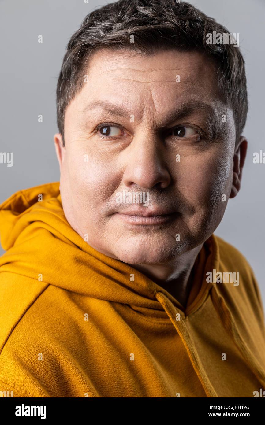 Portrait en gros plan d'un beau homme confiant, regardant loin avec calme expression, soins de santé et beauté masculins, portant un sweat à capuche de style urbain. Prise de vue en studio isolée sur fond gris. Banque D'Images