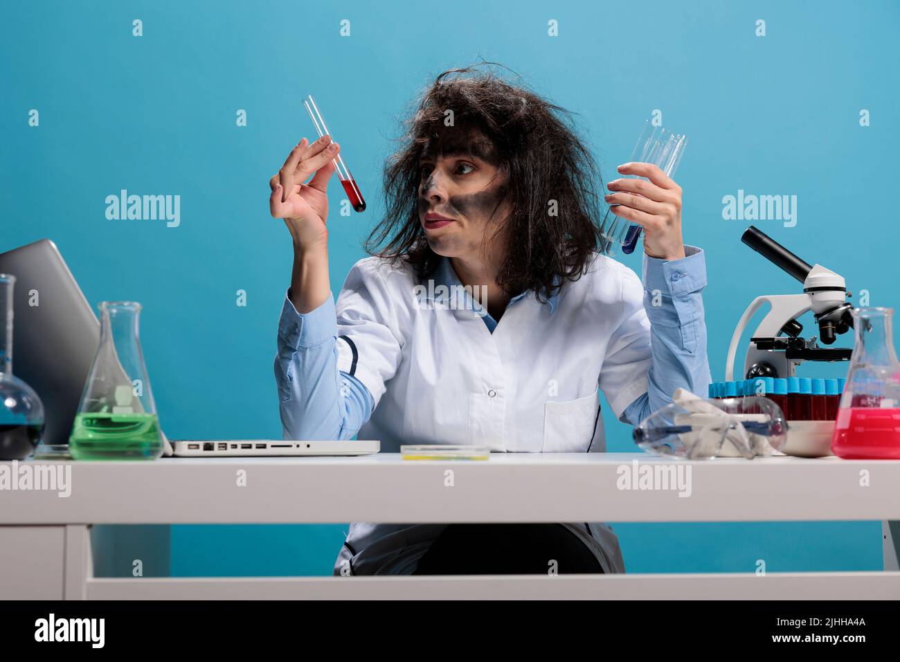 Scientifique fou avec aspect goofy en laboratoire d'examen de substance  liquide. Insense sauvage et folle chimiste analysant des tubes  essai en  verre remplis d'chantillons de sang tout en tant assis au