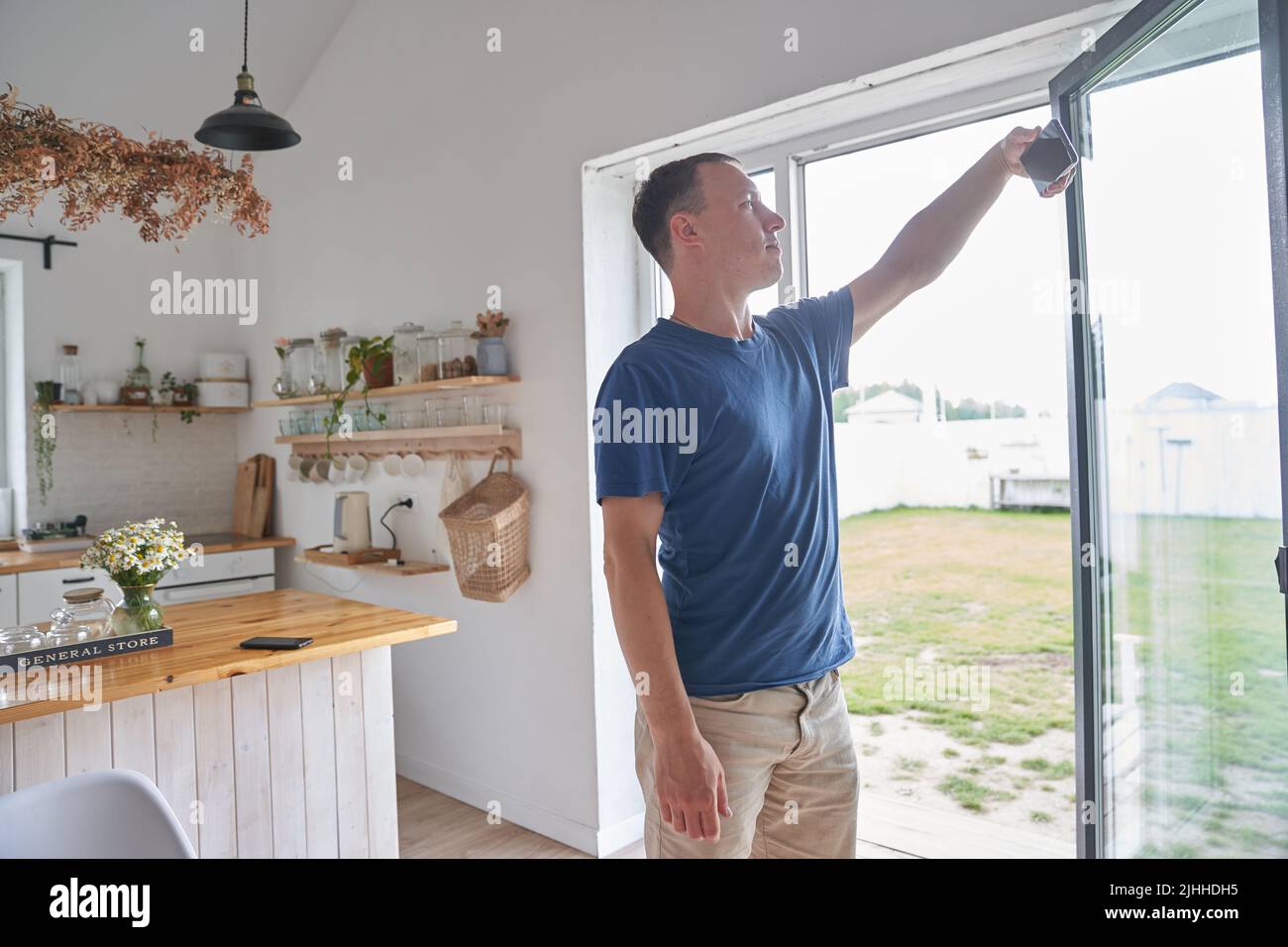 Un jeune homme travaillant à distance depuis son bureau à domicile regarde des informations sur son téléphone. Un homme tient un smartphone entre ses mains et le regarde. Photo de haute qualité Banque D'Images
