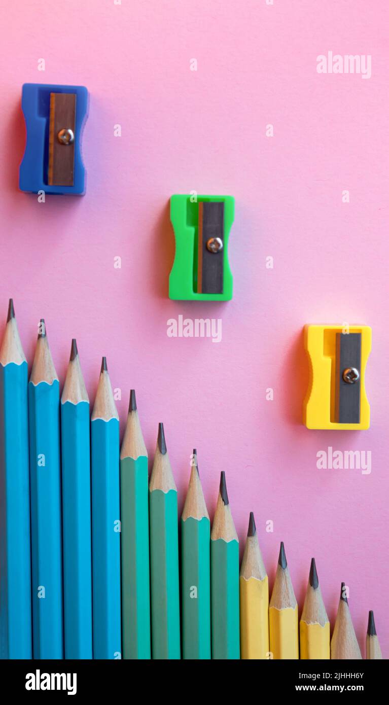 Crayons en bois de couleur et taille-crayon sur fond rose. Vue de dessus, plan d'appartement. Retour à l'école, concept d'éducation. Banque D'Images