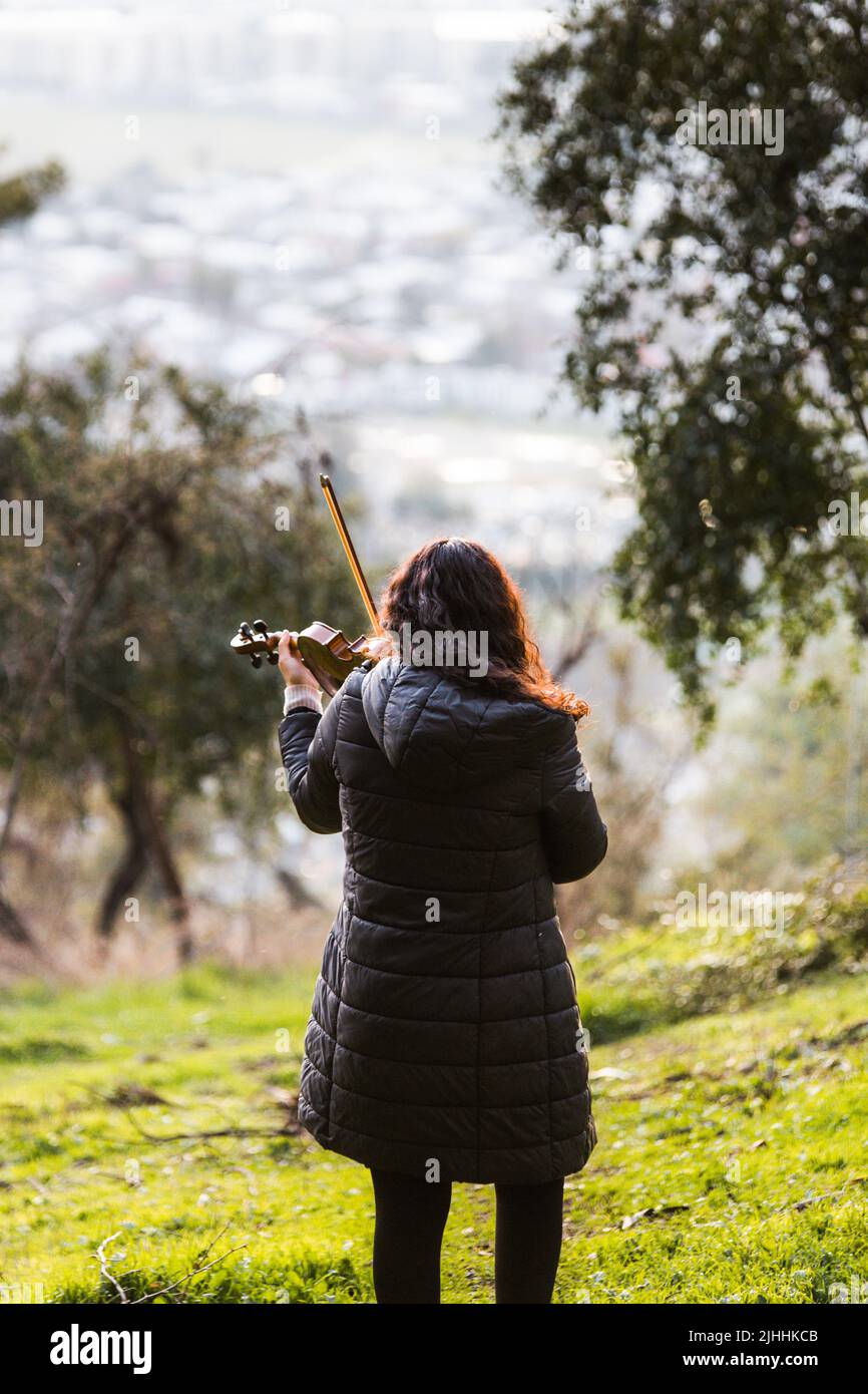 Violoniste Brunette vue de dos jouant du violon à l'extérieur de la montagne. Verticale Banque D'Images