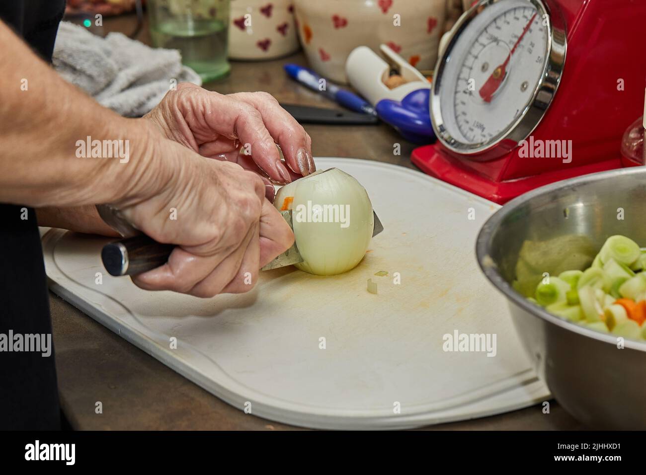Le chef coupe l'oignon en tranches sur le tableau dans la cuisine maison Banque D'Images