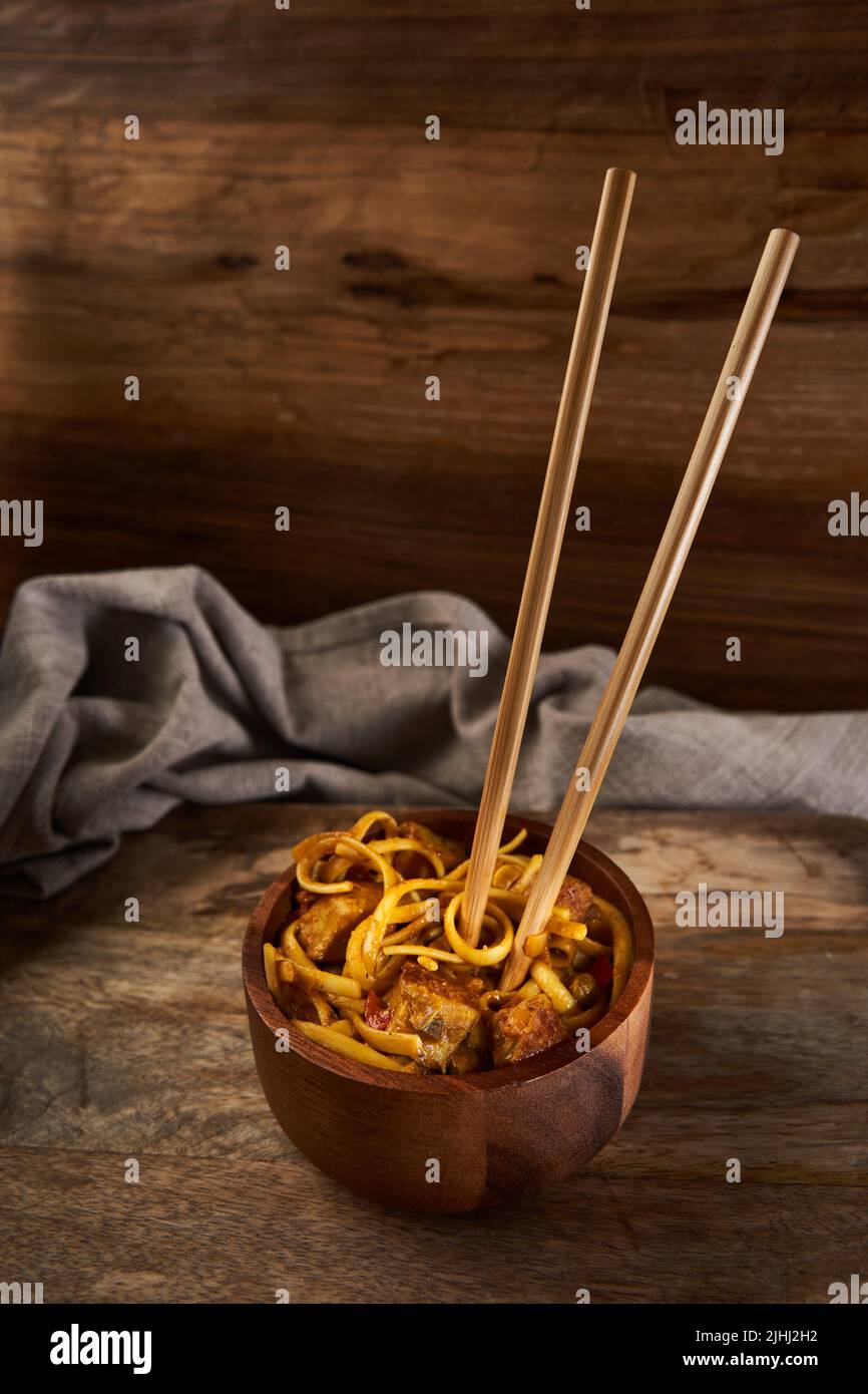Bami Goreng, spécialité indonésienne de pâtes dans un bol en bois avec baguettes Banque D'Images