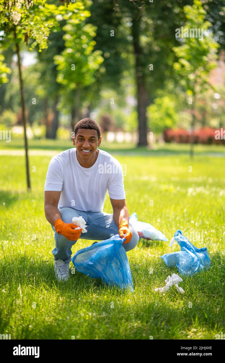 Homme ramassant les déchets dans le parc en regardant la caméra Banque D'Images