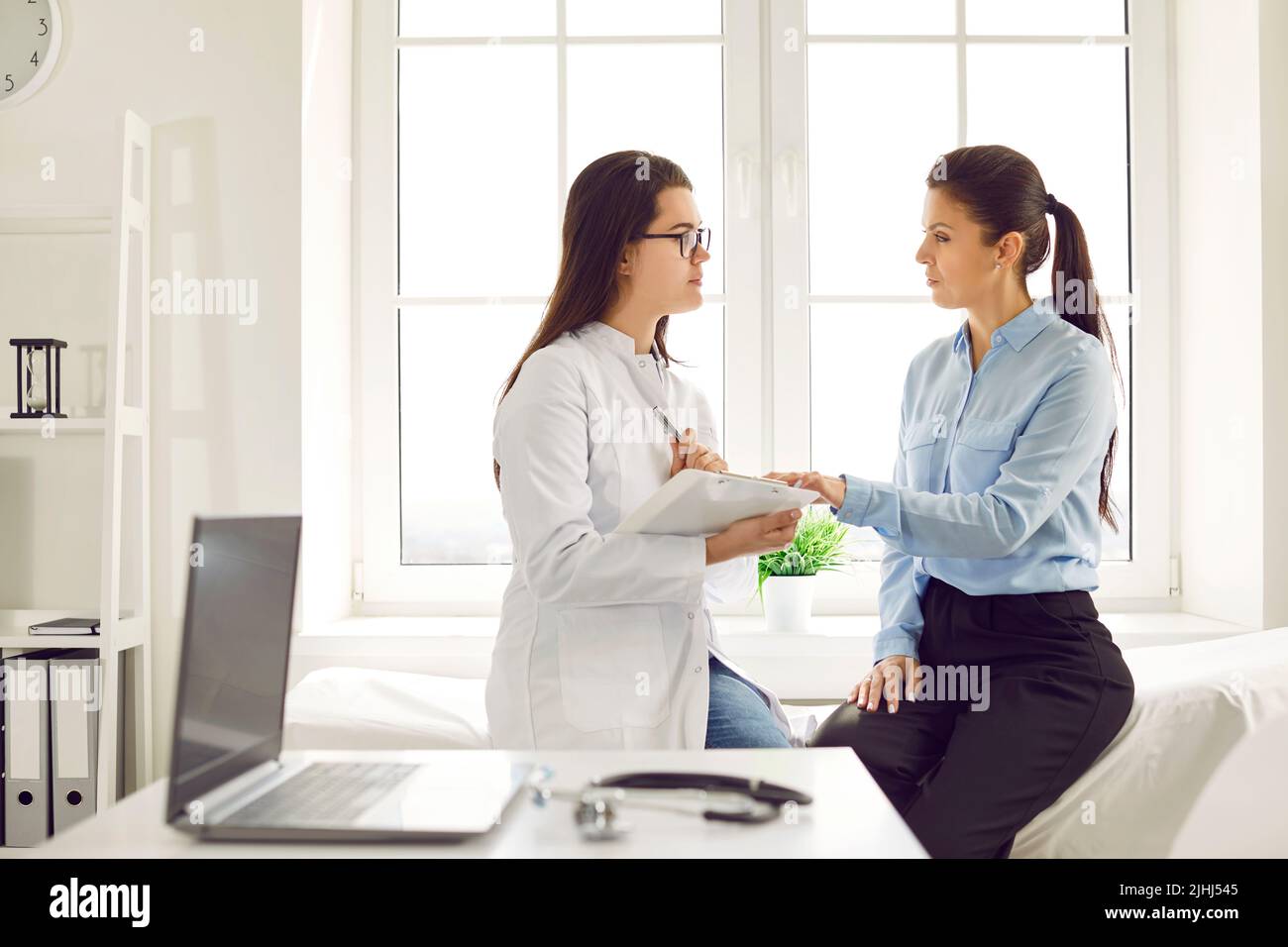 Femme sérieuse voyant un médecin généraliste dans une clinique ou un bureau médical moderne Banque D'Images