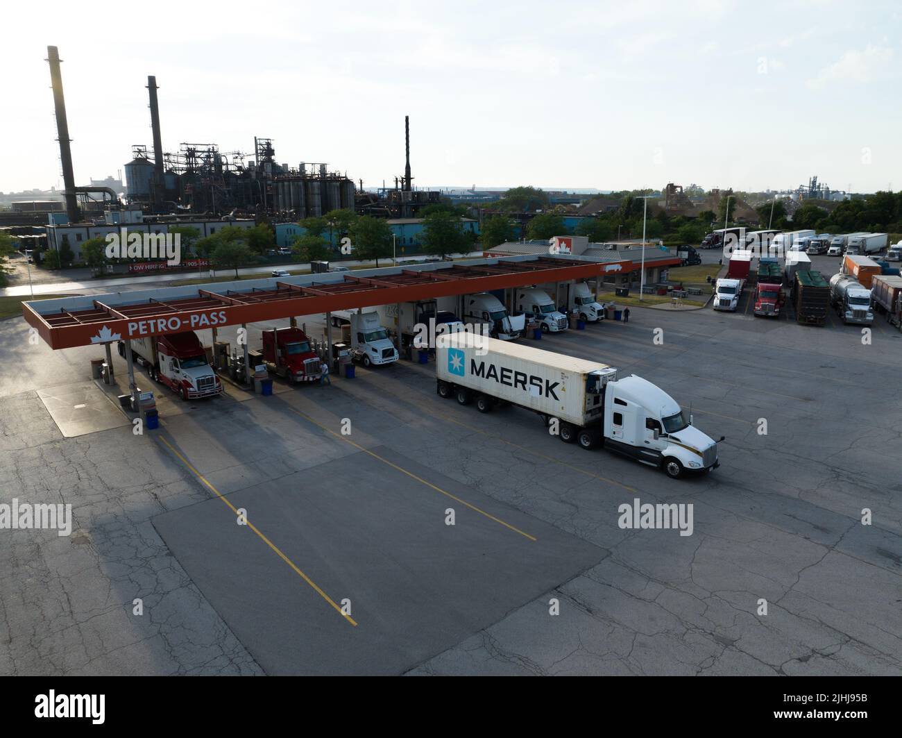Un conteneur Maersk sur un camion de transport quitte une grande station-service dans un secteur industriel un après-midi ensoleillé. Banque D'Images