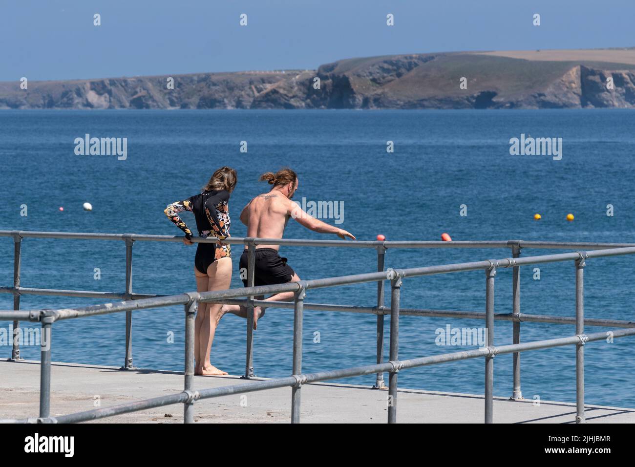 Un holidaymaker sautant d'un quai dans le port de Newquay avec son partenaire à regarder en Cornouailles en Angleterre au Royaume-Uni. Banque D'Images