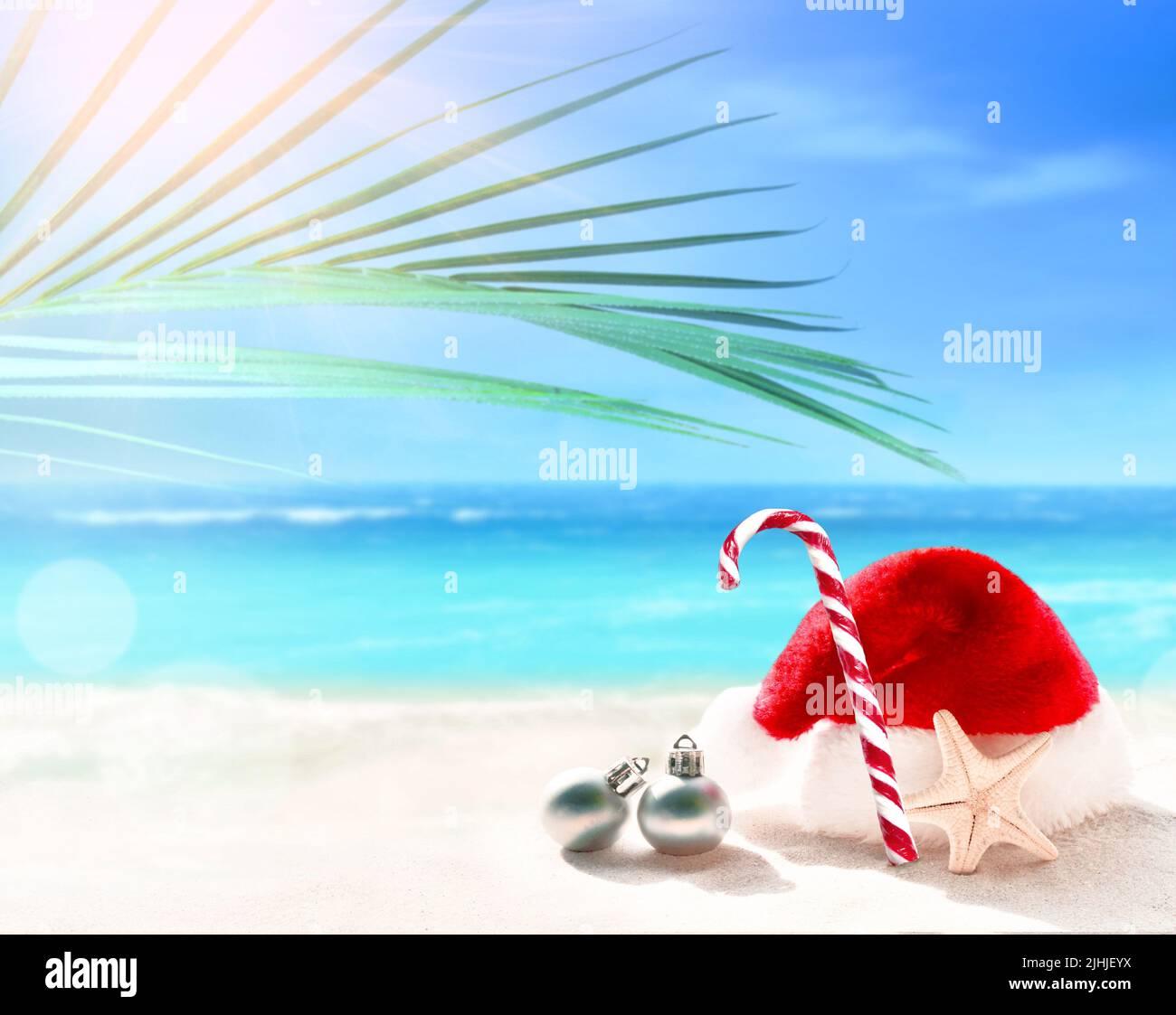 Chapeau et bonbon du Père Noël sur sable blanc de plage tropicale - concept de vacances de Noël ou du nouvel an. Banque D'Images
