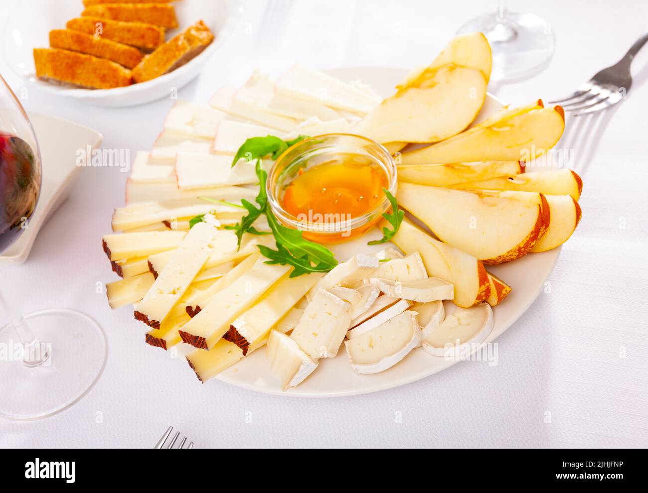 Assiette avec différents types de fromage et une tasse de miel Banque D'Images