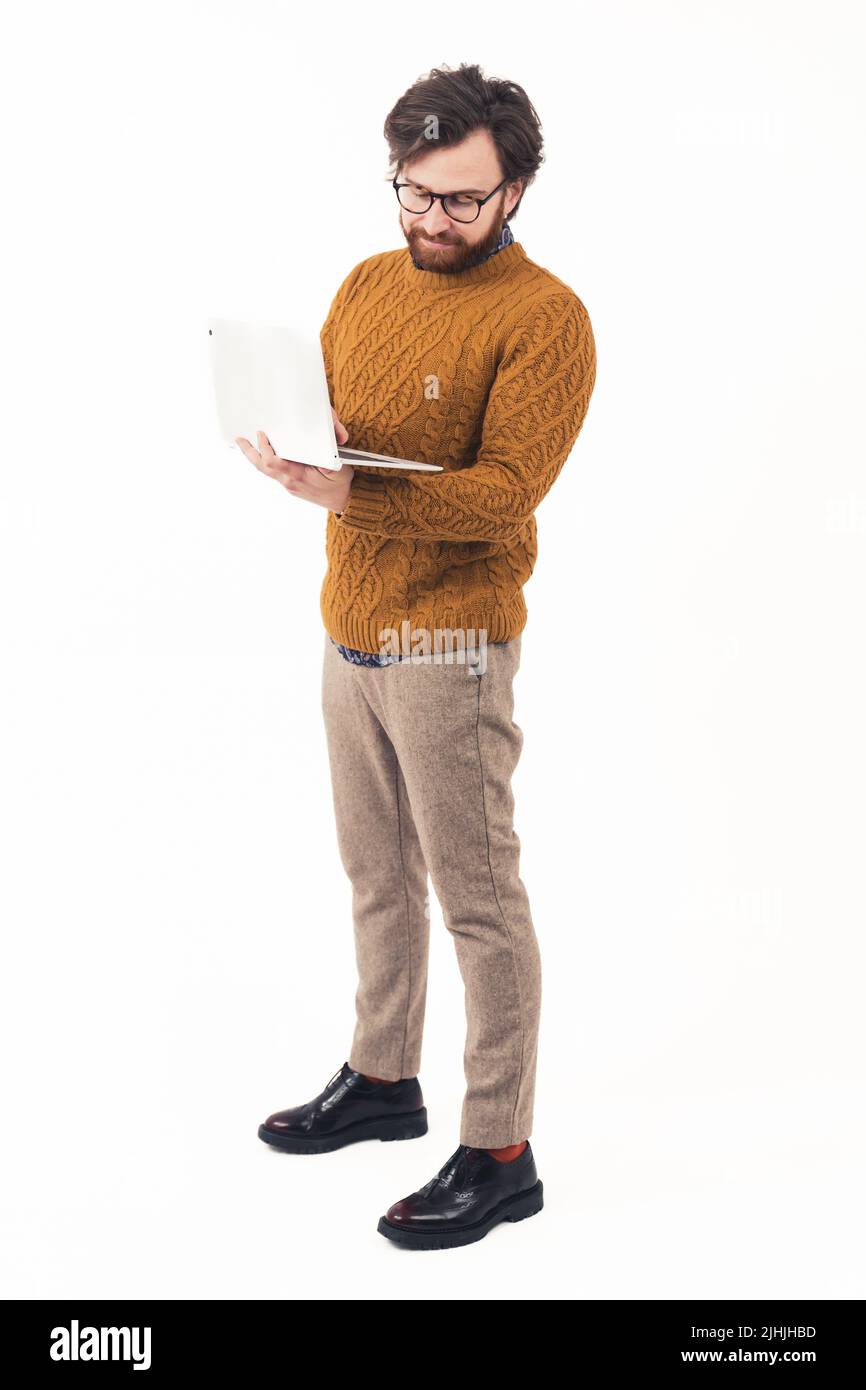 Homme élégant et bien entretenu avec l'ordinateur portable debout et dactylographiant - isolé sur fond blanc. Photo de haute qualité Banque D'Images