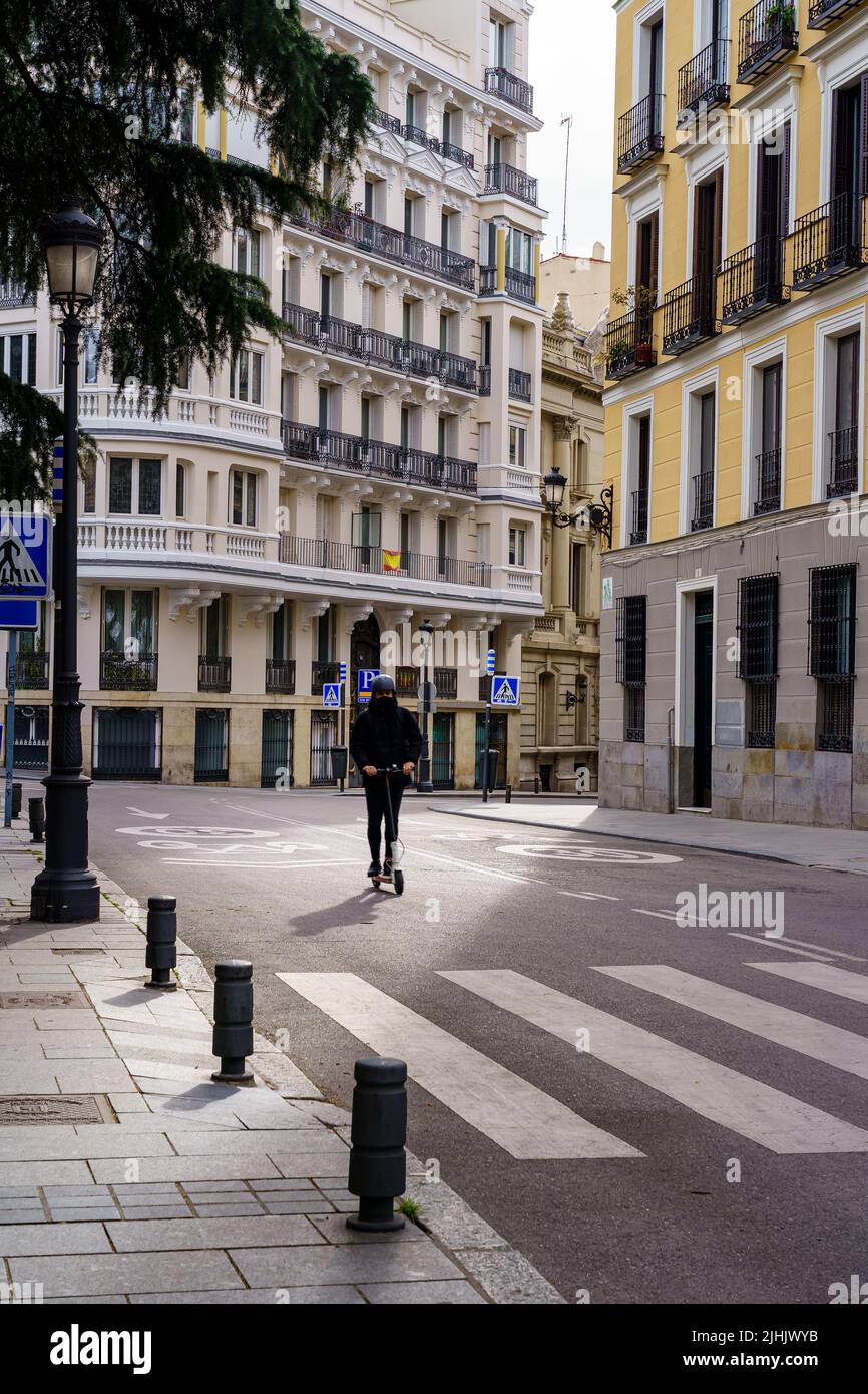 Homme sur un scooter électrique à travers les rues de Madrid, sans véhicules à moteur, un matin de printemps. Espagne. Banque D'Images