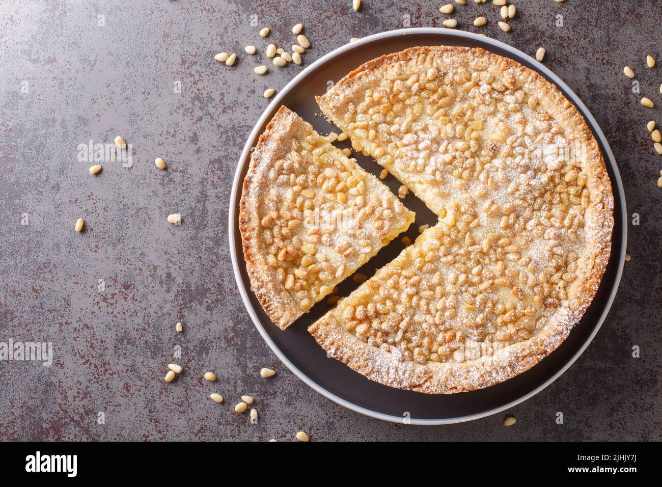 Gâteau italien recouvert de pignons de pin connu sous le nom de torta della nonna closeup dans l'assiette sur la table. Vue horizontale du dessus Banque D'Images