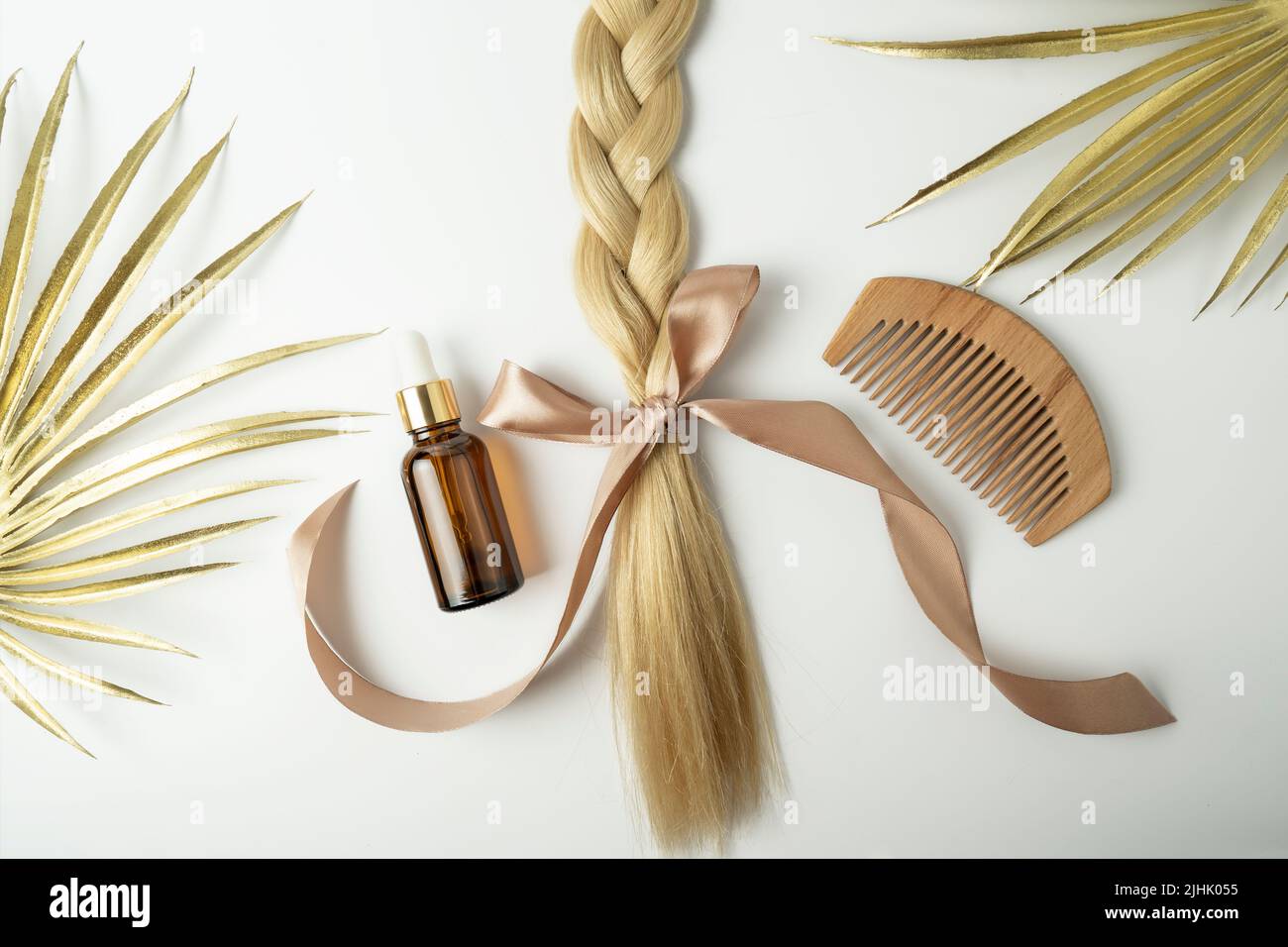 Cheveux blonds naturels et huile essentielle pour le traitement des cheveux couché sur un fond blanc Banque D'Images