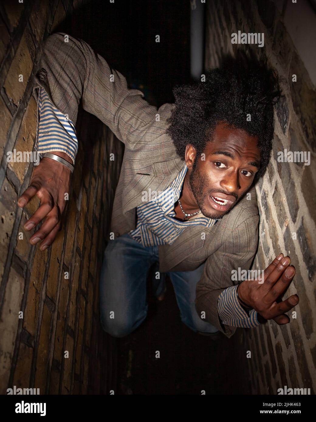 Peur urbaine. Langage corporel anxieux d'un personnage vulnérable piégé dans une ruelle sombre et étroite. D'une série d'images avec le même modèle. Banque D'Images