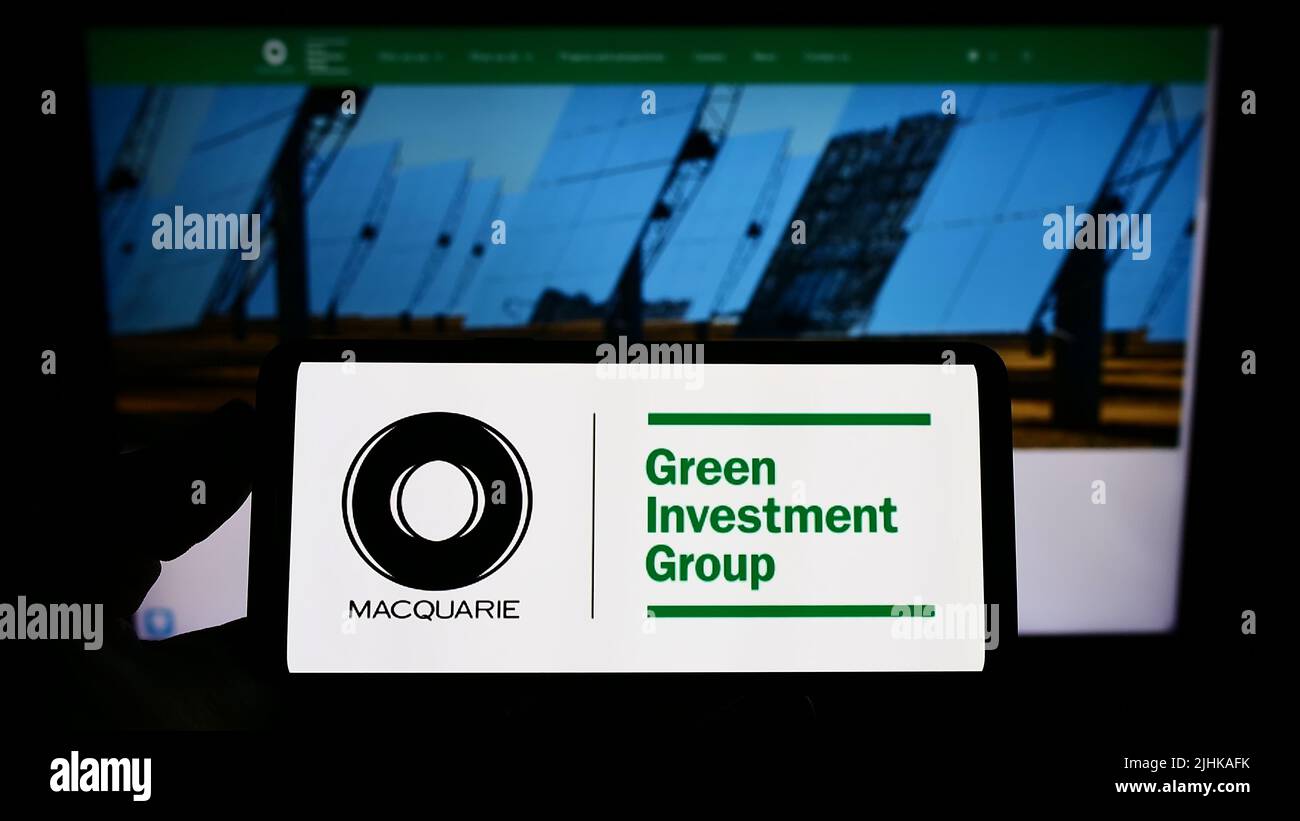 Personne tenant un smartphone avec le logo de la société Green Investment Group Limited (GIG) à l'écran devant le site Web. Mise au point sur l'affichage du téléphone. Banque D'Images