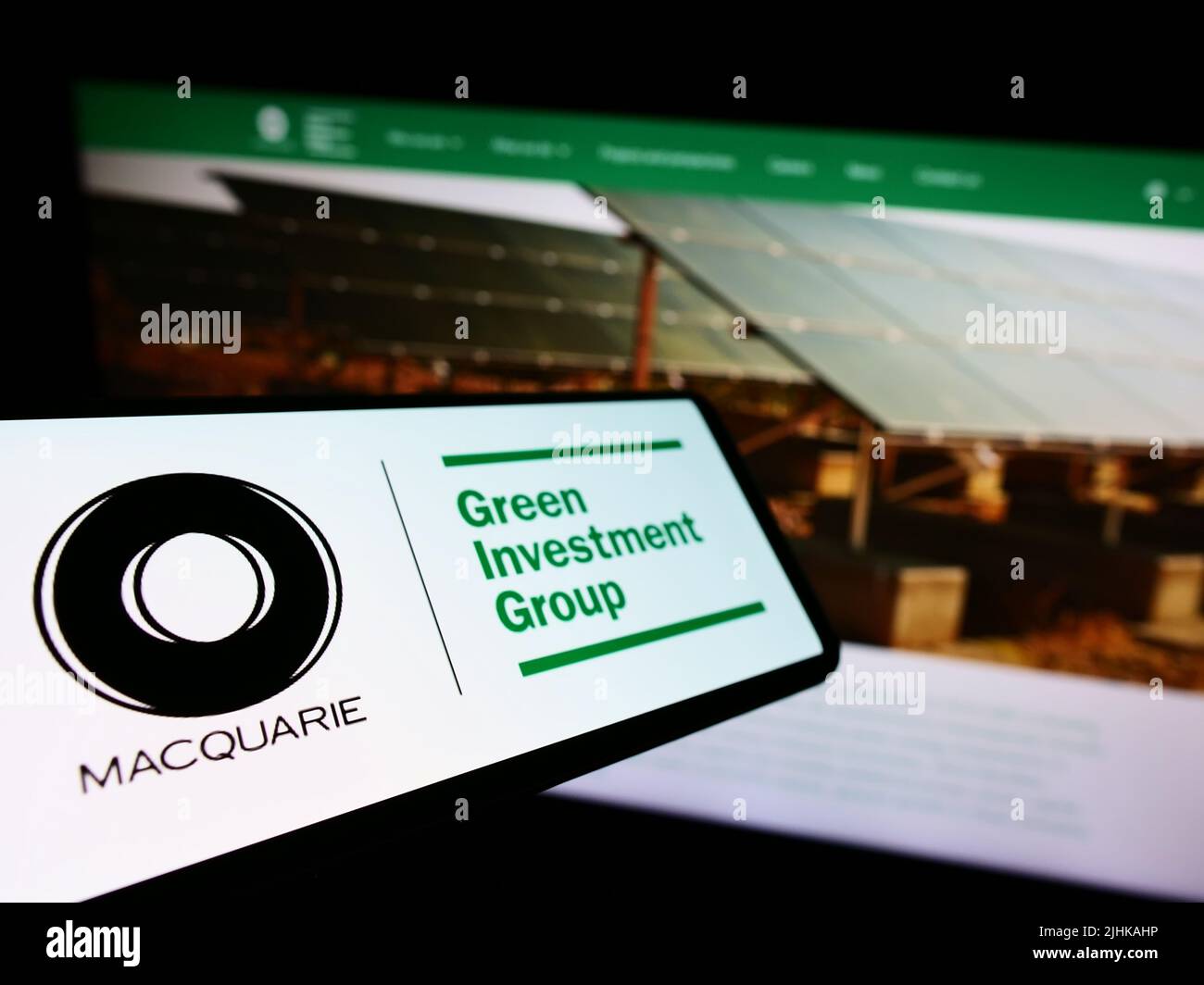 Téléphone portable avec logo de la société Green Investment Group Limited (GIG) à l'écran devant le site Web d'affaires. Mise au point au centre-gauche de l'écran du téléphone. Banque D'Images