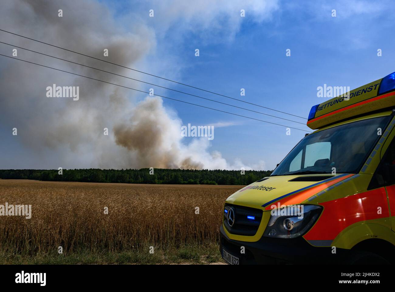 Radeburg, Allemagne. 19th juillet 2022. De la fumée s'élève d'une forêt sur le Königsbrücker Heide près de Radeburg tandis qu'une ambulance passe. Crédit : Robert Michael/dpa/Alay Live News Banque D'Images