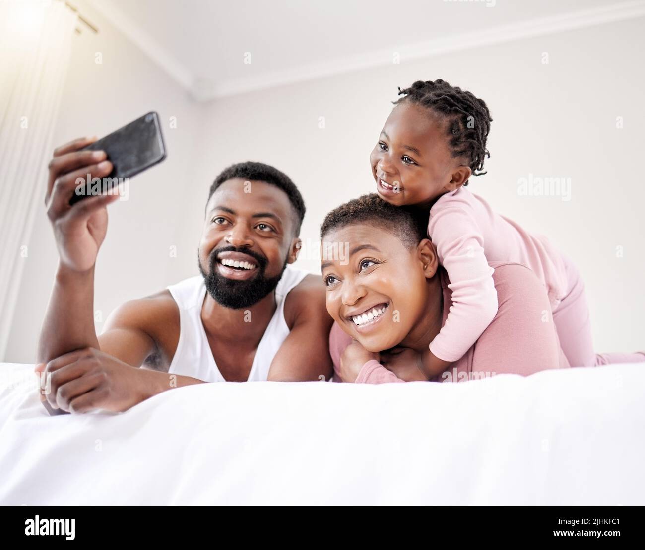 Montrez au monde mes bijoux. Une jeune famille se liant dans le lit ensemble. Banque D'Images