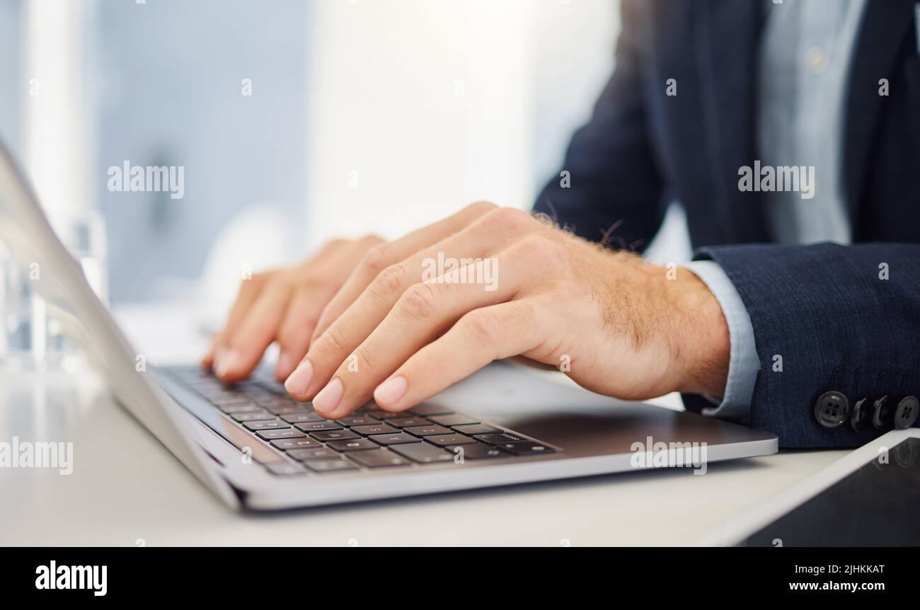 Gros plan sur un homme d'affaires caucasien tapant sur un clavier d'ordinateur portable dans un bureau. Mains d'un entrepreneur en appuyant sur les boutons pour envoyer un courriel et parcourir le Banque D'Images