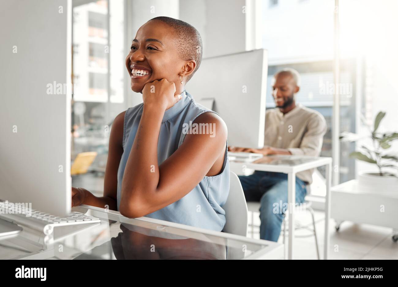 Jeune femme d'affaires afro-américaine joyeuse utilisant un ordinateur de bureau dans un bureau au travail. Femme d'affaires noire gaie lisant un e-mail à un Banque D'Images