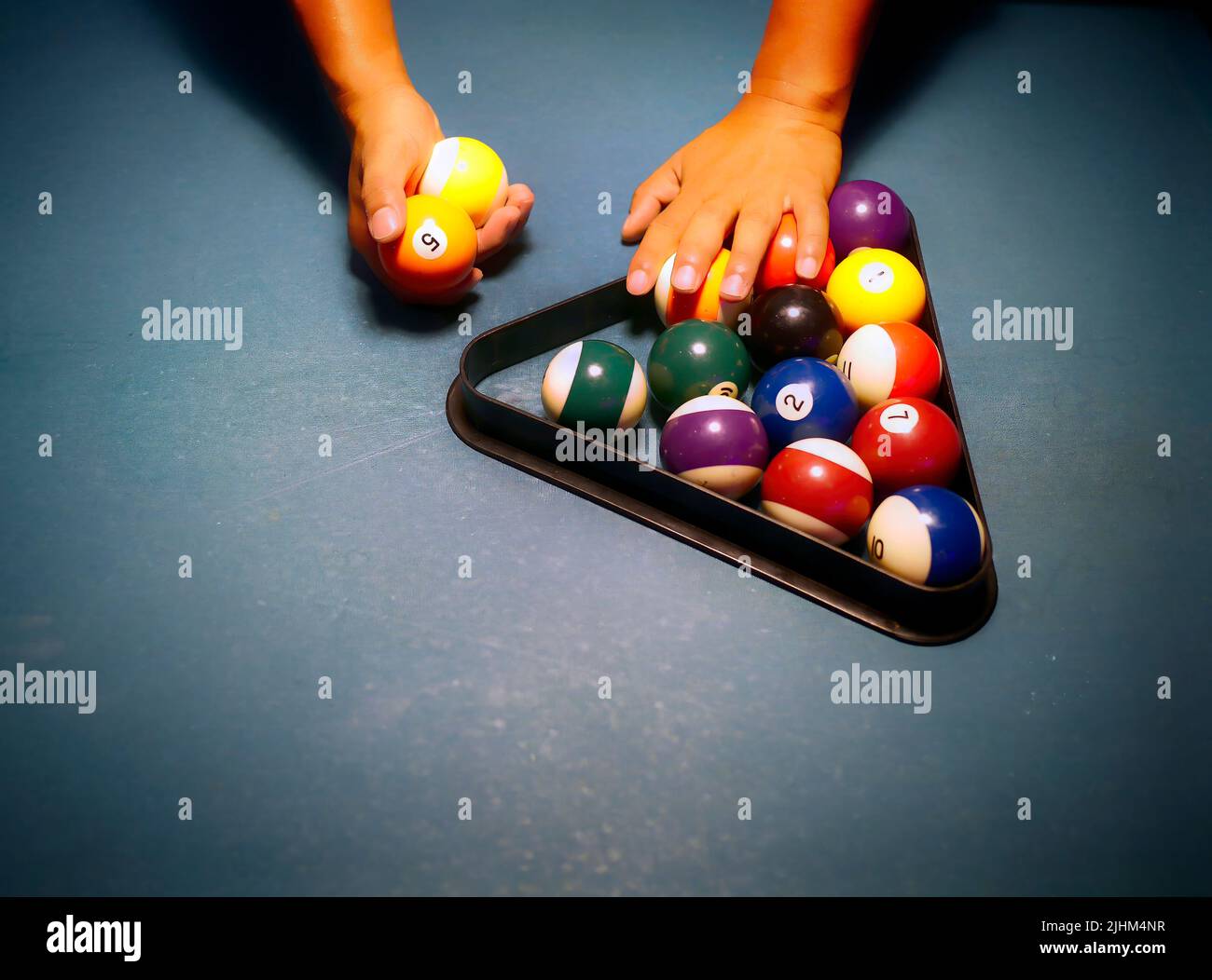 Mains préparant des boules de billard dans un rack triangulaire sur la table de billard Banque D'Images