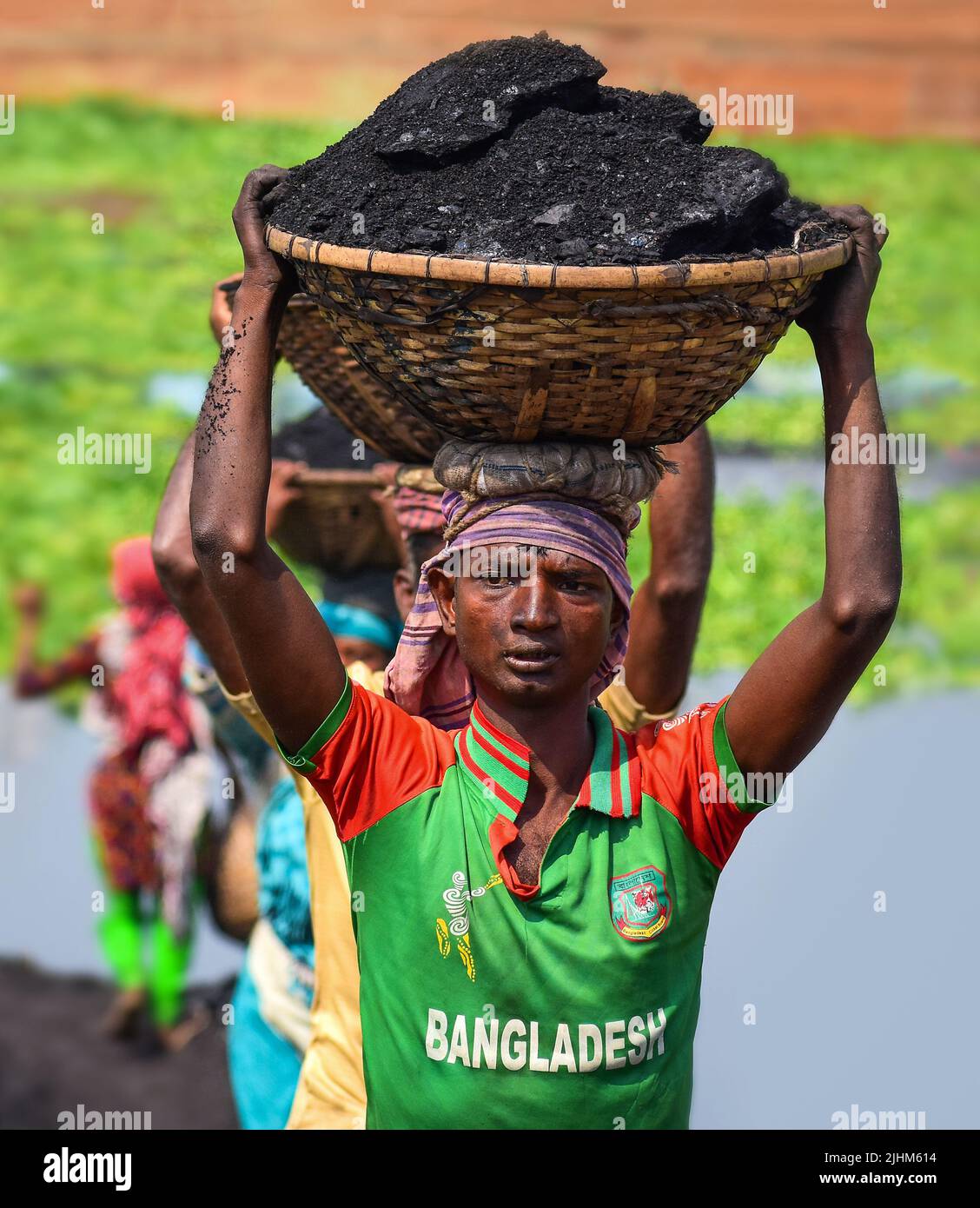 Les travailleuses transportant des paniers remplis de charbon sur leur tête dans la région de Gabtoli à Dhaka Banque D'Images