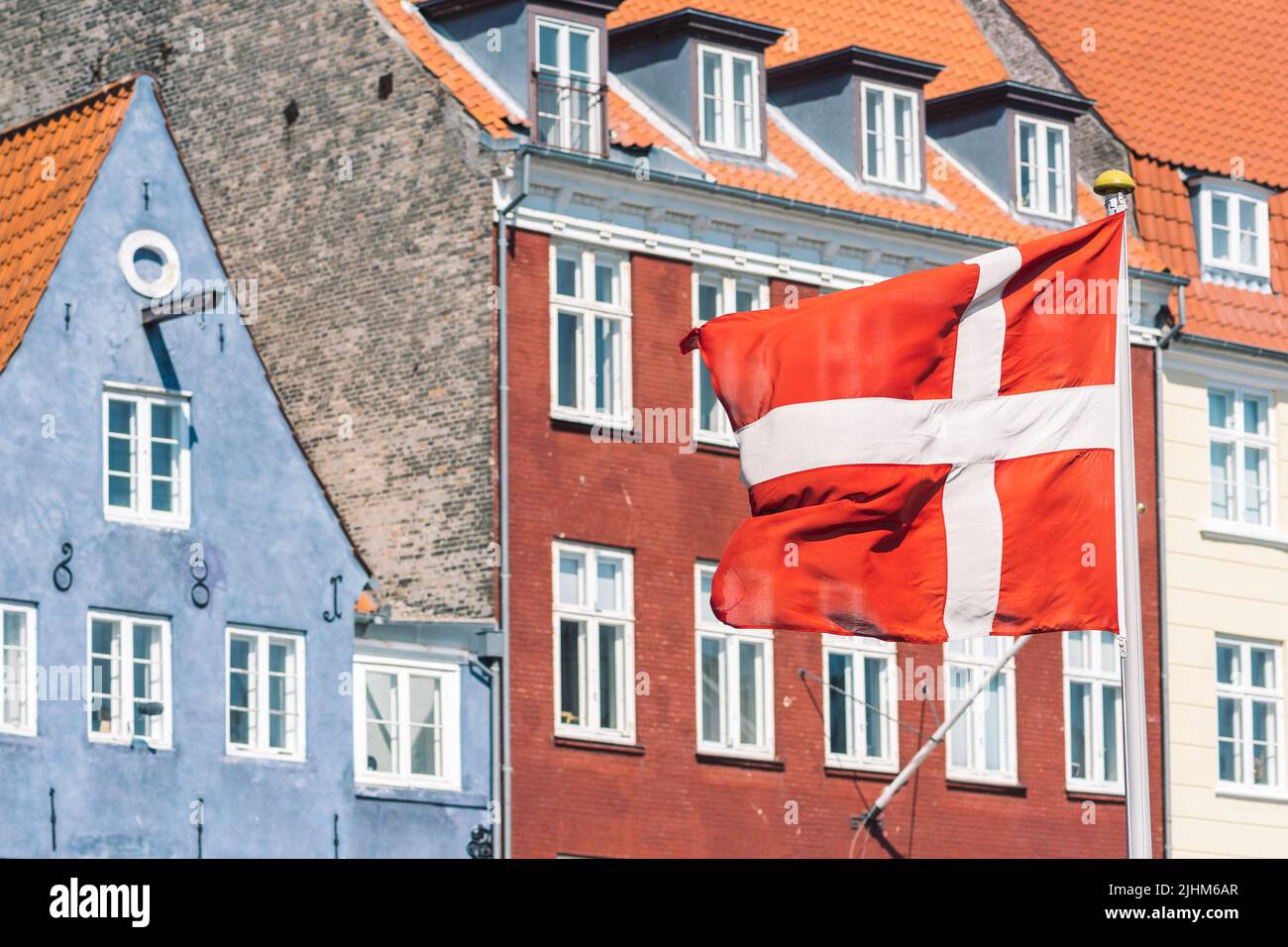 Façade colorée de vieilles maisons traditionnelles le long du canal de Nyhavn ou du nouveau port, canal et quartier de divertissement à Copenhague avec drapeau danois Banque D'Images