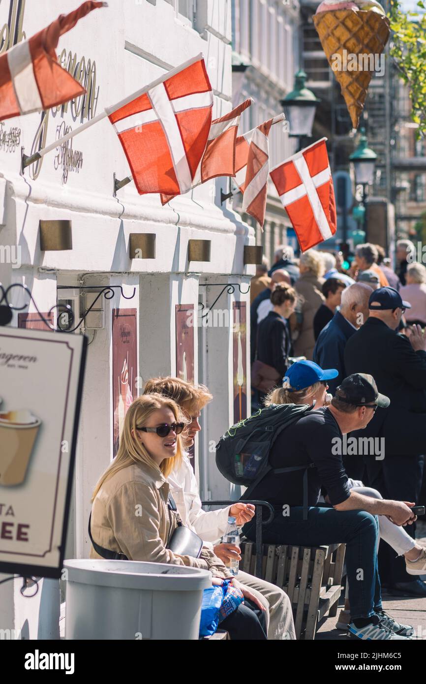 Touristes au canal de Nyhavn ou New Harbour, canal et quartier de divertissement à Copenhague, Danemark, avec drapeaux danois, vertical Banque D'Images