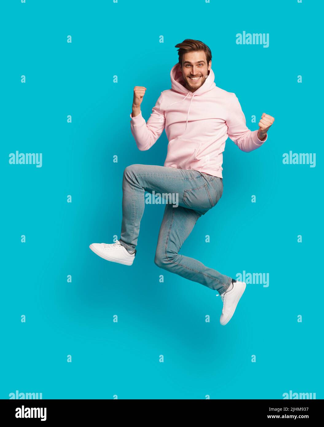 Photo pleine grandeur de jeune heureux excité souriant positif homme sautant isolé sur fond bleu clair de couleur Banque D'Images