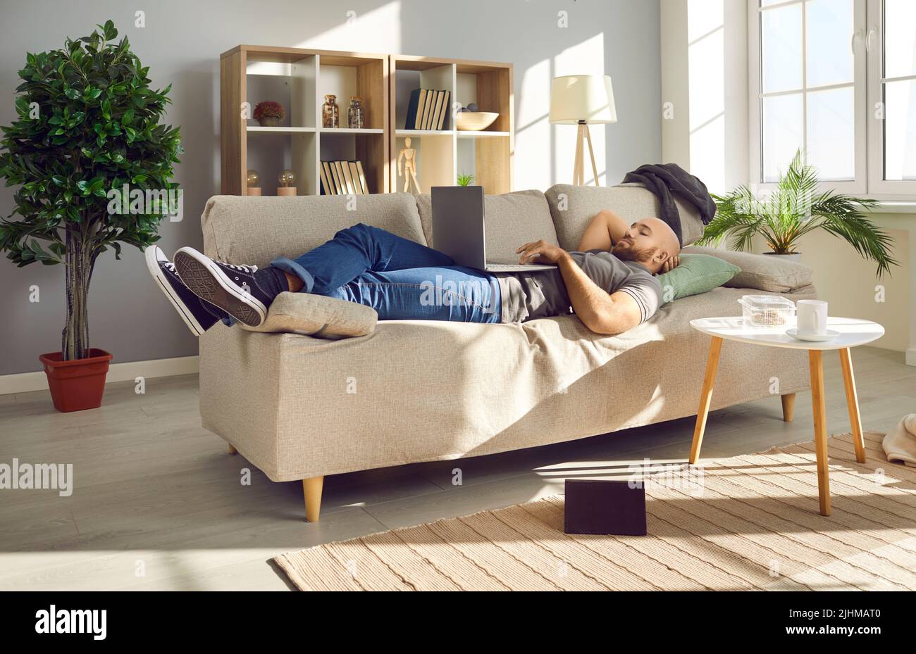 Un jeune homme heureux se reposant sur le canapé à la maison et regardant un film sur son ordinateur portable Banque D'Images