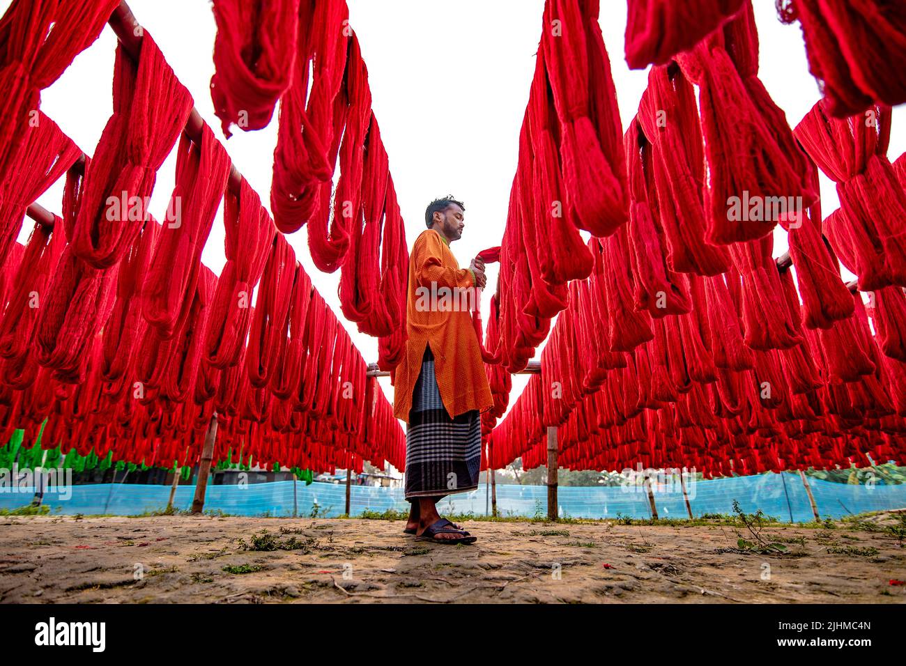 Fils et tissus colorés teints et séchant dans les champs ouverts. Textile, vêtements, mode, teinture de tissu, fait à la main, procédé de séchage, artisanat rural Banque D'Images