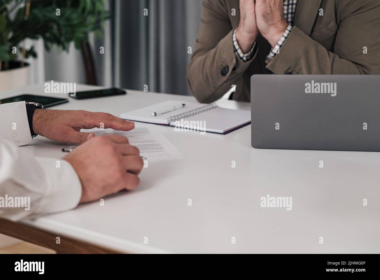 Un collègue de sexe masculin assis avec un ordinateur portable, un entrepreneur principal examine les papiers à son bureau. Ils sont assis au bureau et brainstorming. Banque D'Images