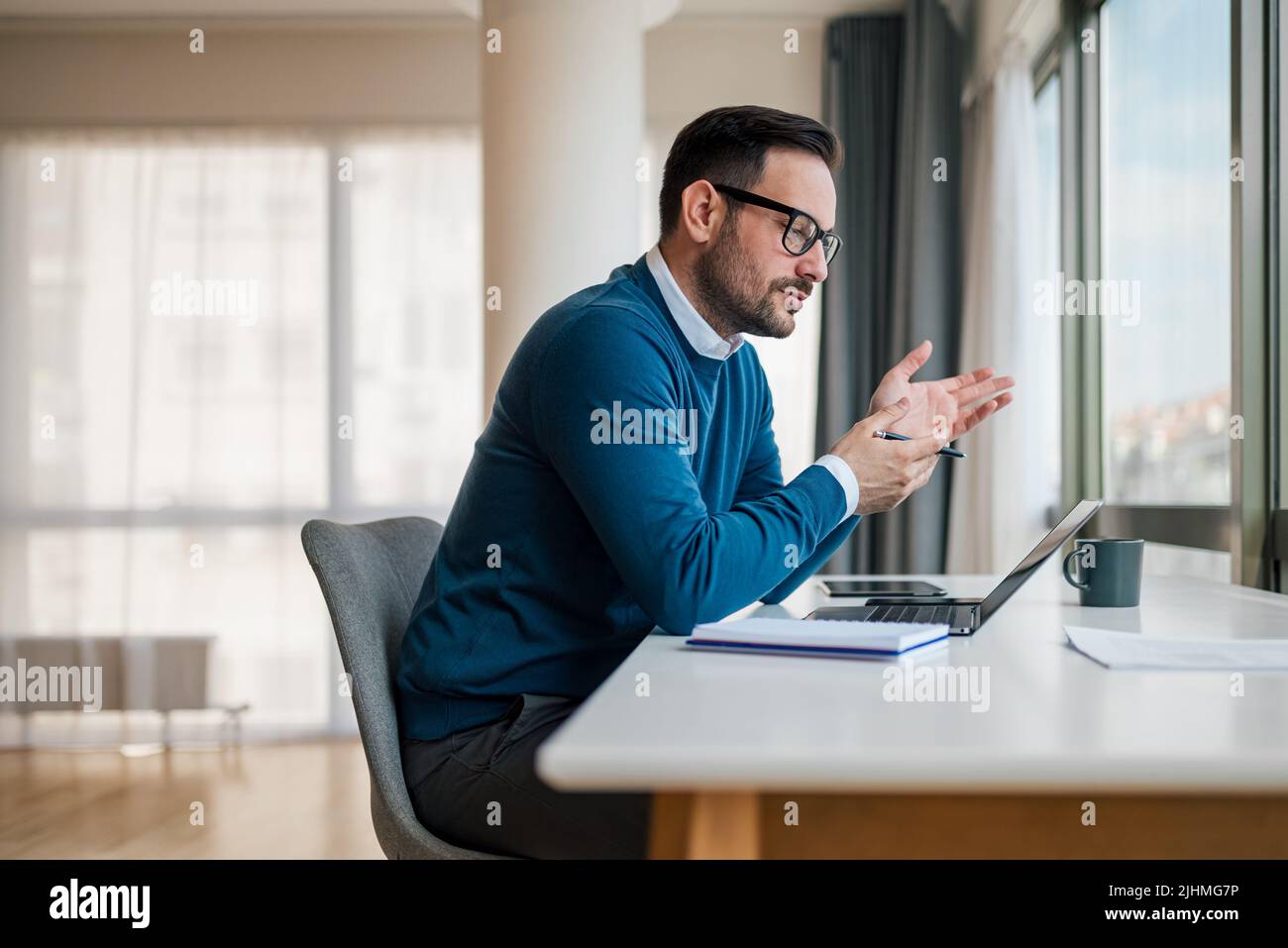 Homme d'affaires confiant analysant le plan sur un ordinateur portable. Jeune professionnel travaillant assis au bureau. Il a une réunion d'affaires en ligne en entreprise de Banque D'Images