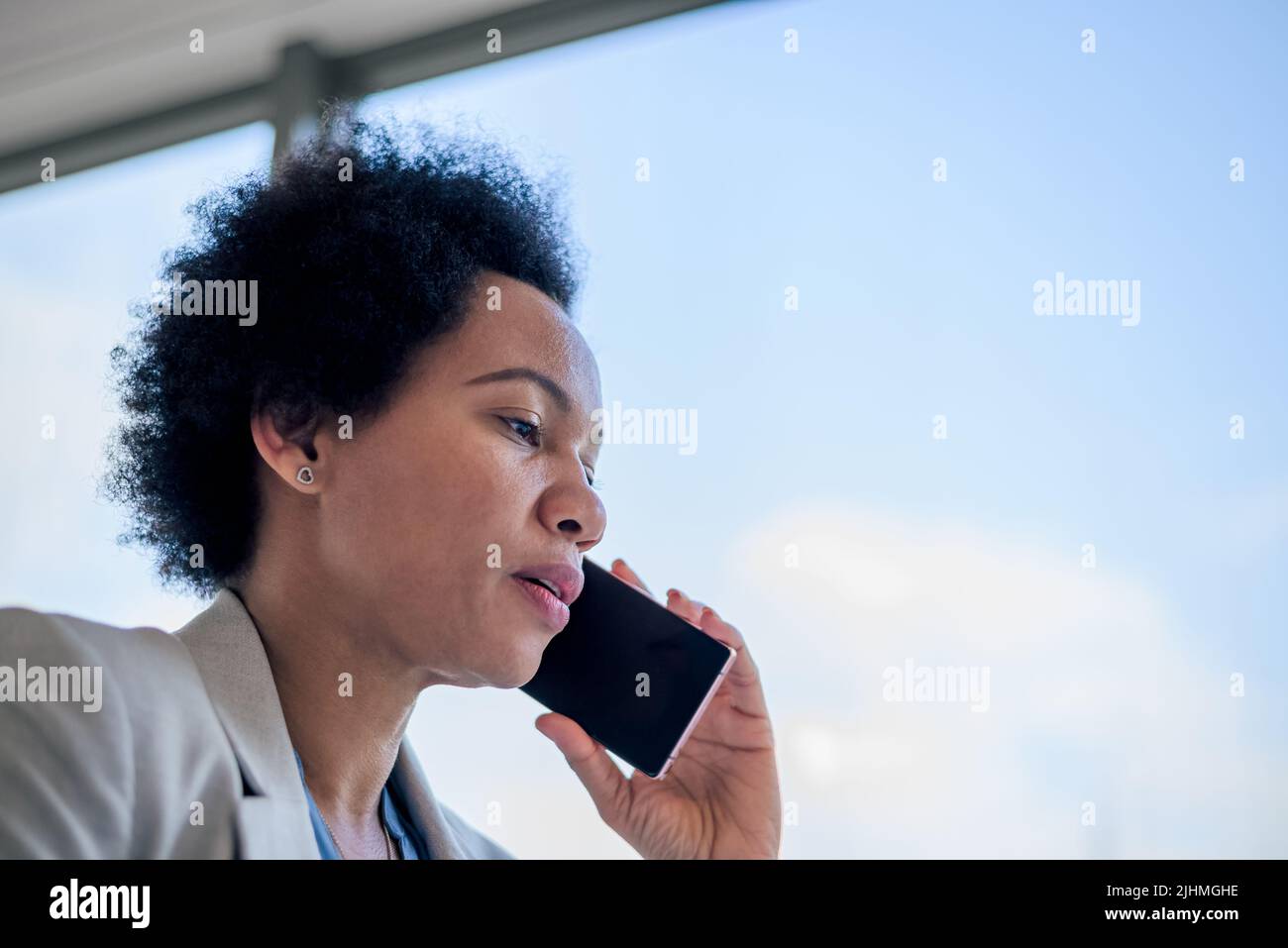 Femme d'affaires tentée parlant sur un smartphone. La femme de direction se trouve près de la fenêtre. Elle est en format officiel au siège social. Banque D'Images