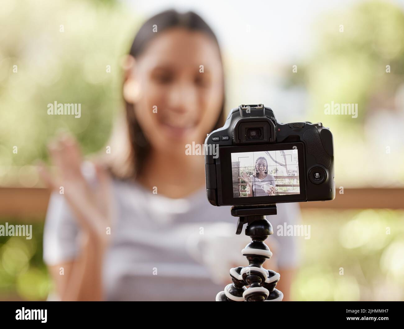 Blogging est ma passion. Une jeune femme assise seule à l'extérieur et utilisant son appareil photo pour vlog. Banque D'Images