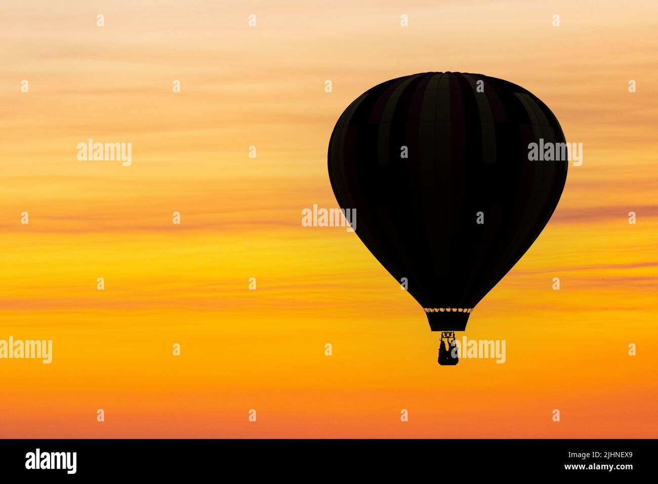 Un ballon d'air chaud est silhoueté contre le ciel au coucher du soleil dans une image composite. Banque D'Images