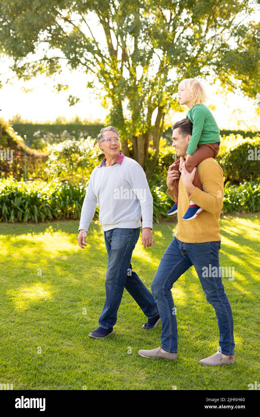 Image verticale d'hommes blancs heureux de trois générations marchant dans le jardin Banque D'Images
